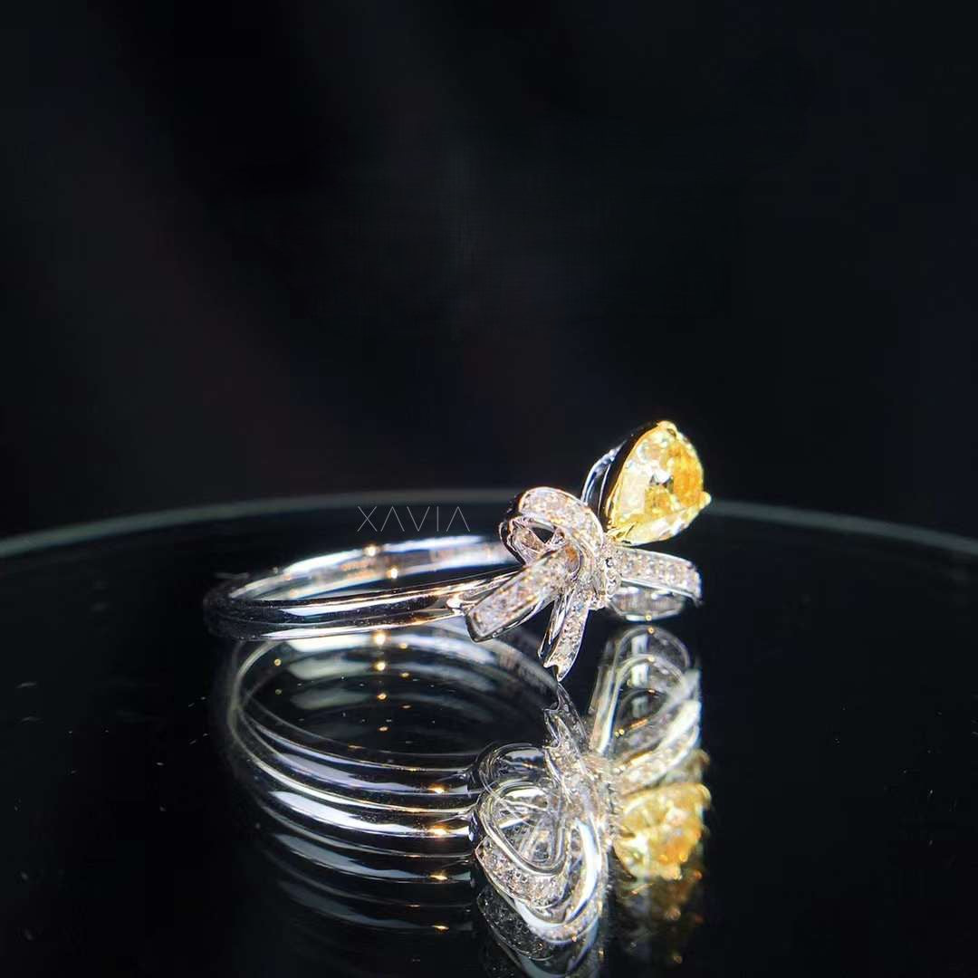 angled view of fancy yellow pear diamond bow ring with pavé-set DEF lab-grown diamonds on polished engagement band