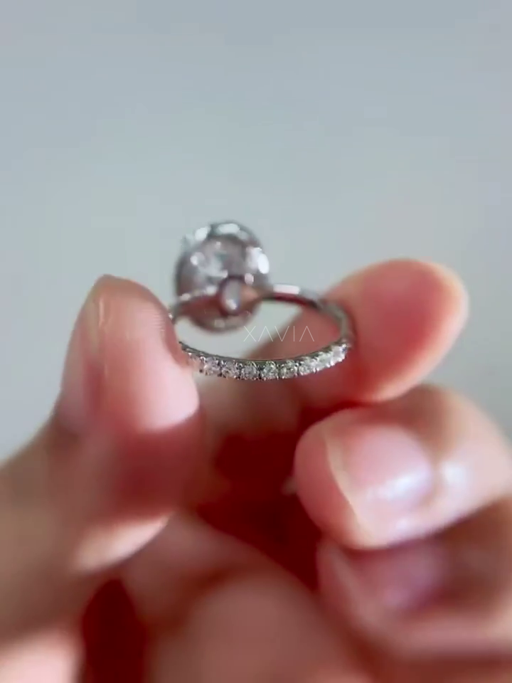 close view of pavé diamond band of oval halo engagement ring highlighting delicate round diamonds set along the slim band in polished metal