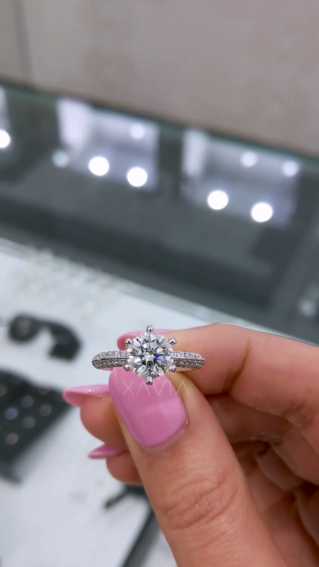 Closeup of round solitaire diamond engagement ring showing pavé split shank and high-polish white gold finish