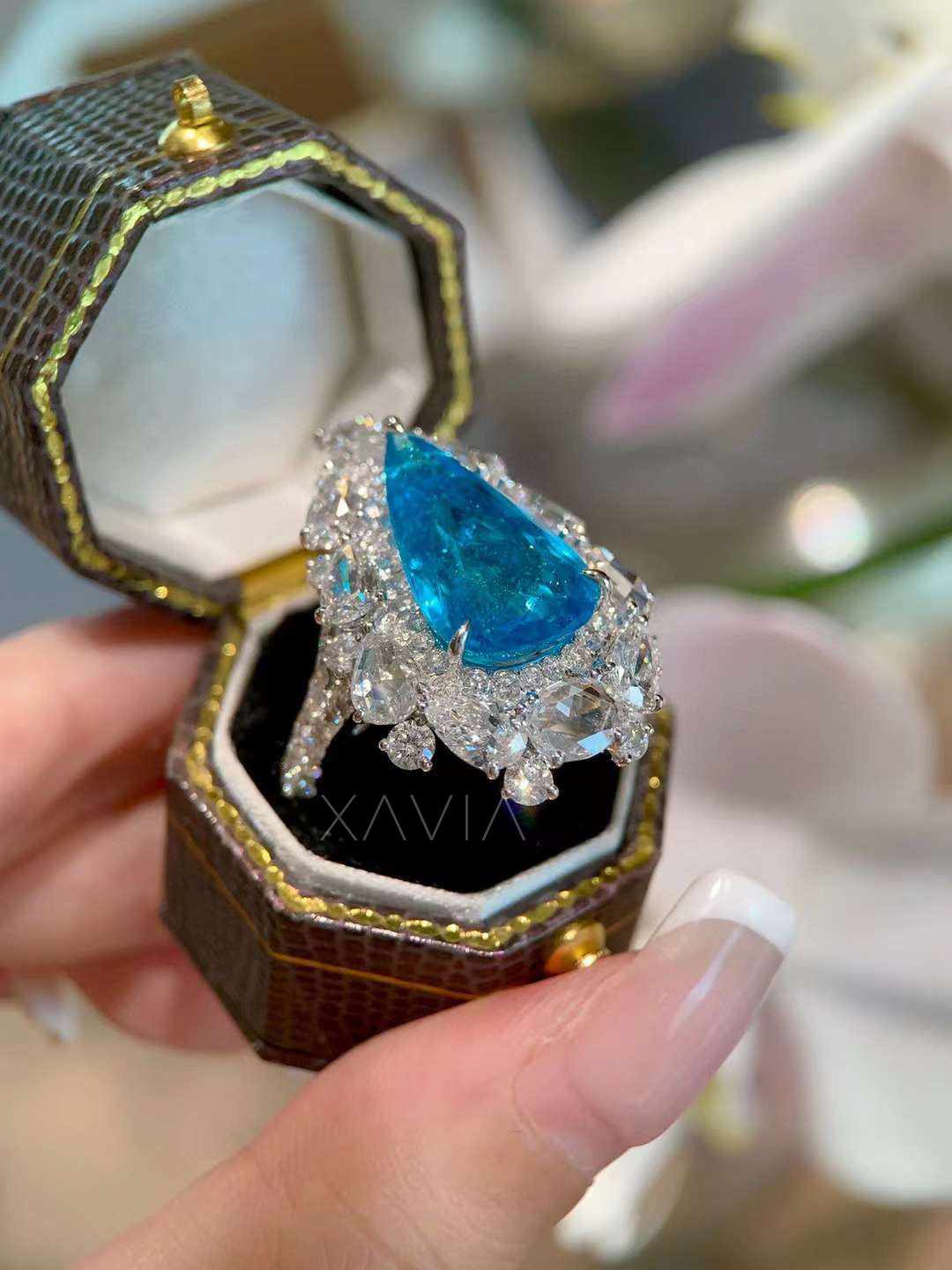 Side profile of pear cut blue gemstone halo cocktail ring showing layered marquise oval and round diamond cluster design in luxurious fine jewelry setting