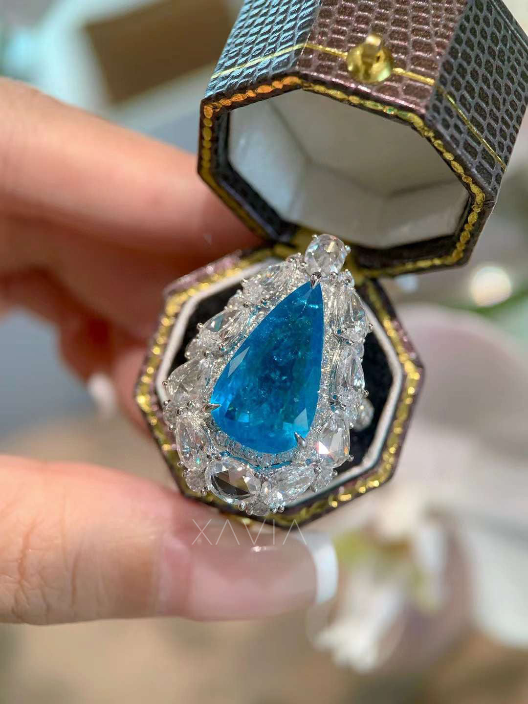 Angled view of pear shaped blue gemstone statement ring with intricate marquise and oval lab grown diamond halo cluster creating brilliant high jewelry sparkle