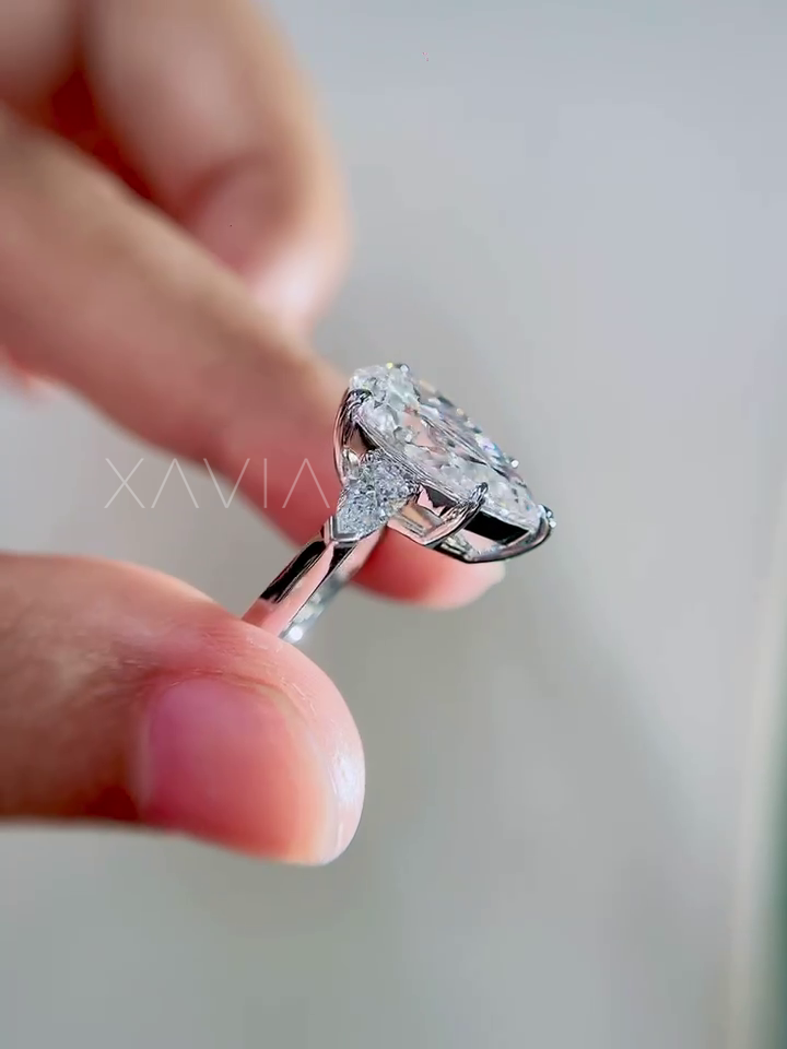 side profile view of pear cut lab grown diamond three stone engagement ring with trillion side diamonds and polished cathedral band
