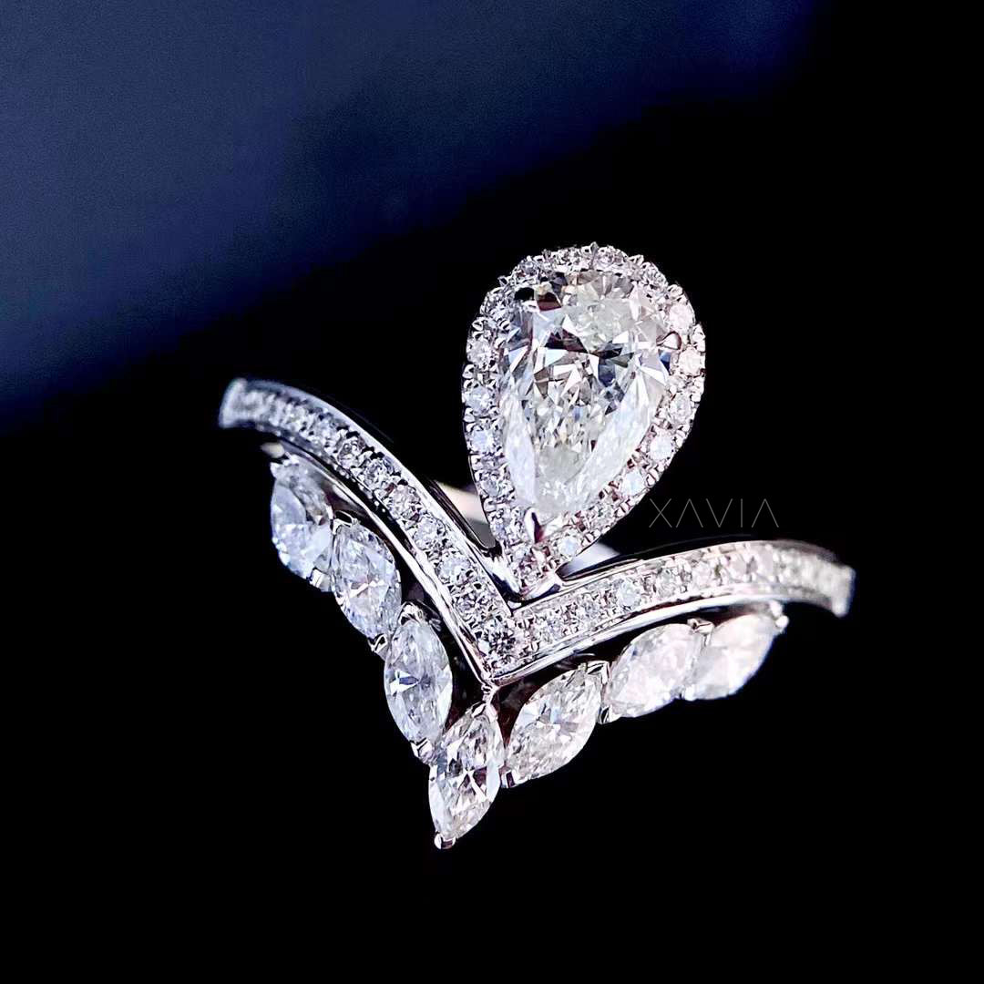 Pear cut halo lab grown diamond ring photographed on black background showing marquise leaf accents and curved bypass shank