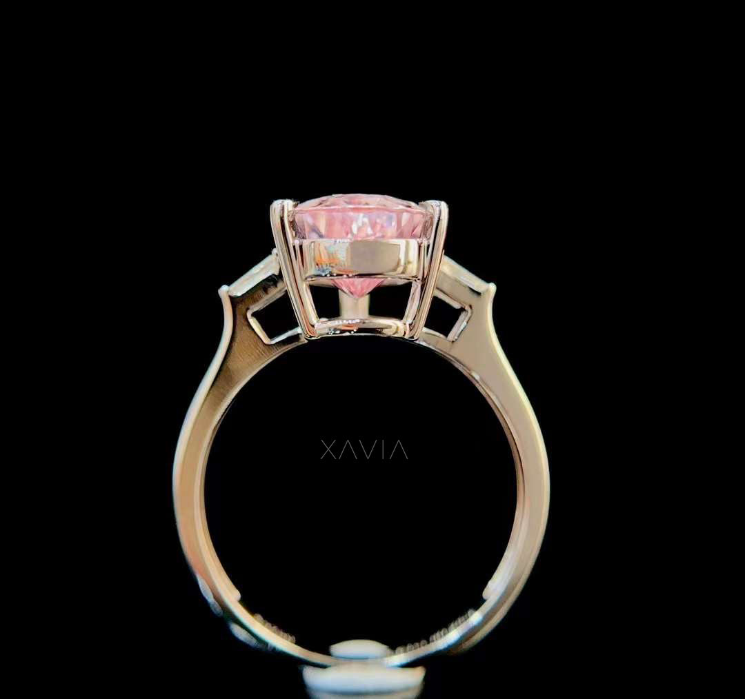 Angled view of pear cut blush morganite ring highlighting brilliance of gemstone and clean tapered baguette diamond side stones in luxury white gold