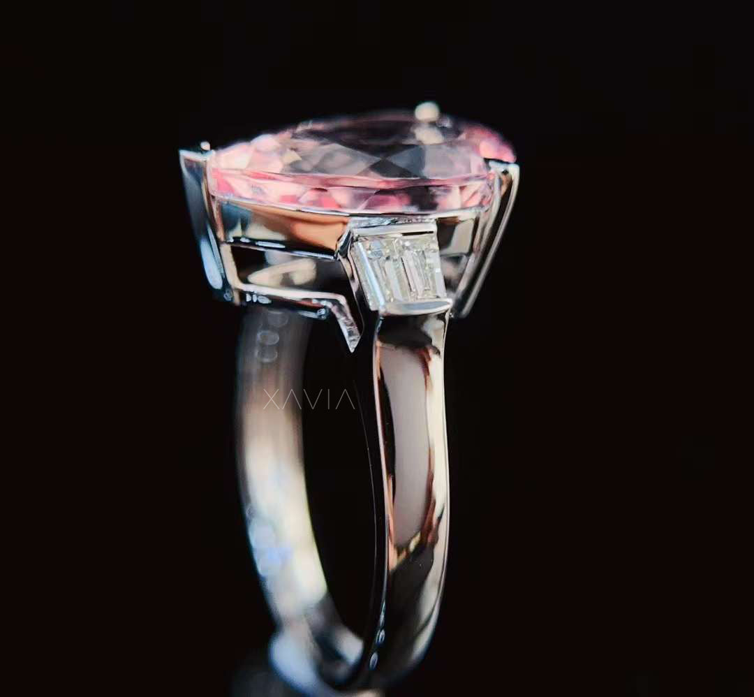 Studio reflection shot of pear shaped pink morganite engagement ring with baguette diamond accents emphasizing gemstone brilliance and luxury craftsmanship