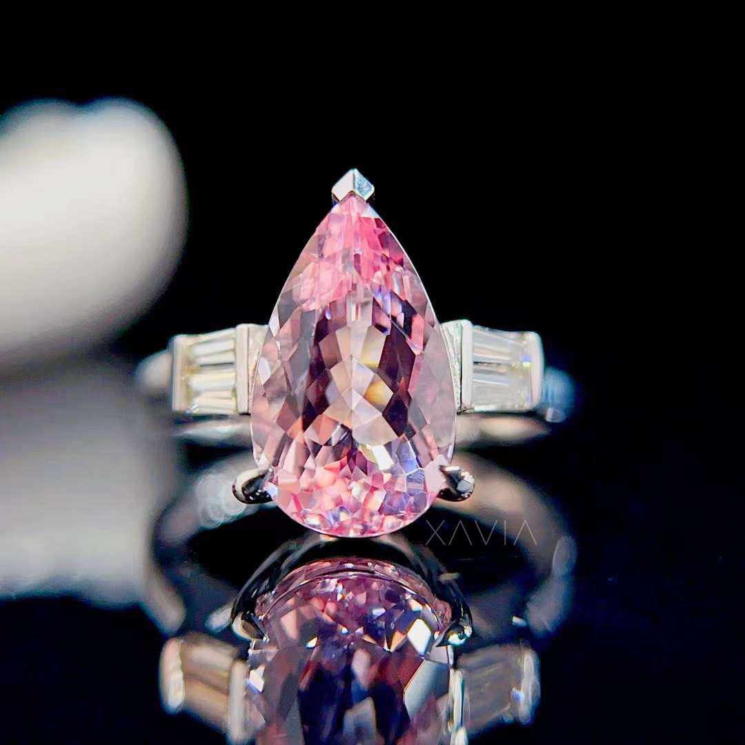 Studio reflection shot of pear shaped pink morganite engagement ring with baguette diamond accents emphasizing gemstone brilliance and luxury craftsmanship
