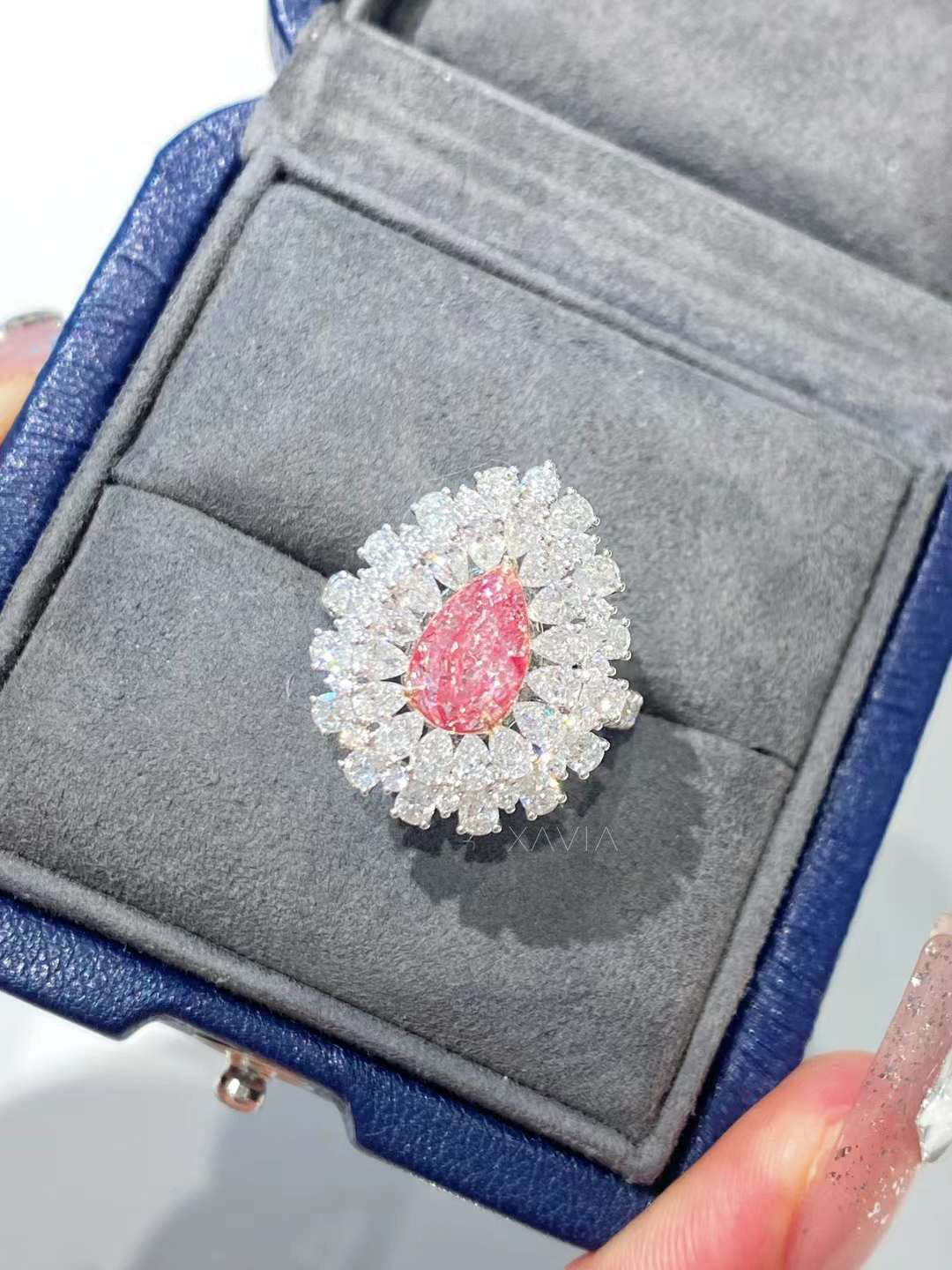 Angled view of pear shaped pink lab grown diamond ring with layered marquise and round diamond halo in polished white gold