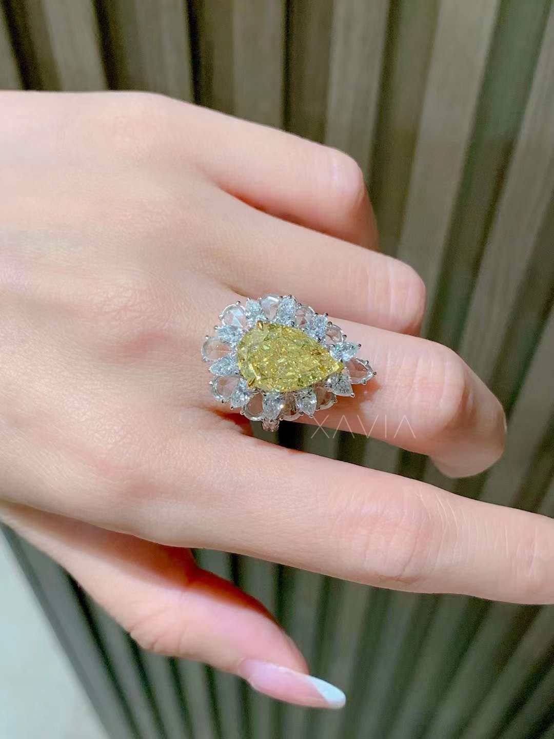 side angled view of pear shaped fancy yellow diamond ring with floral marquise and round diamond halo in white gold setting