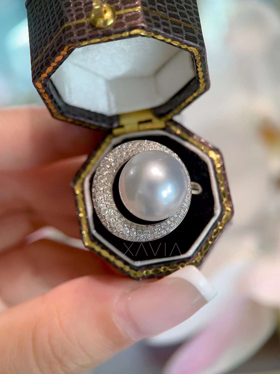 top view of luxury pearl halo ring inside jewelry box featuring round pearl center and pavé diamond crescent halo in high polish setting