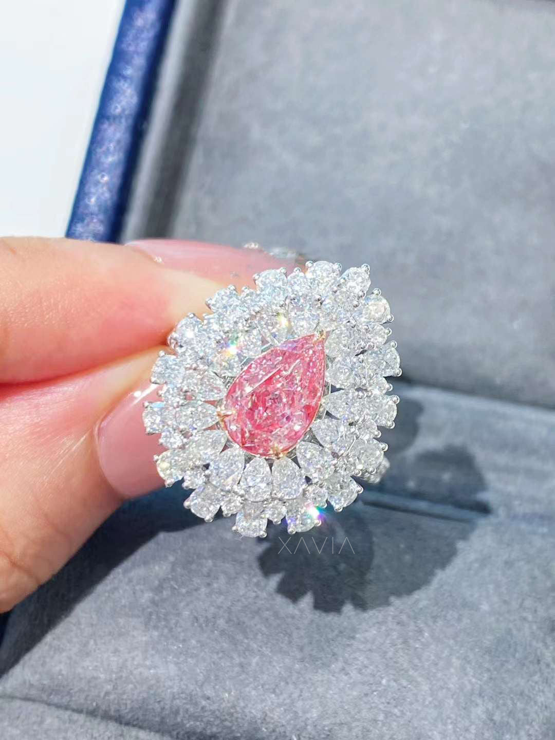 Close-up of pear cut pink lab diamond surrounded by marquise halo diamonds showing detailed prong setting and intense sparkle