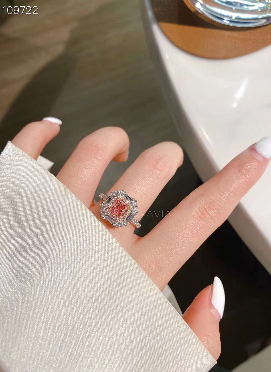 pink cushion diamond engagement ring worn on finger with white shirt