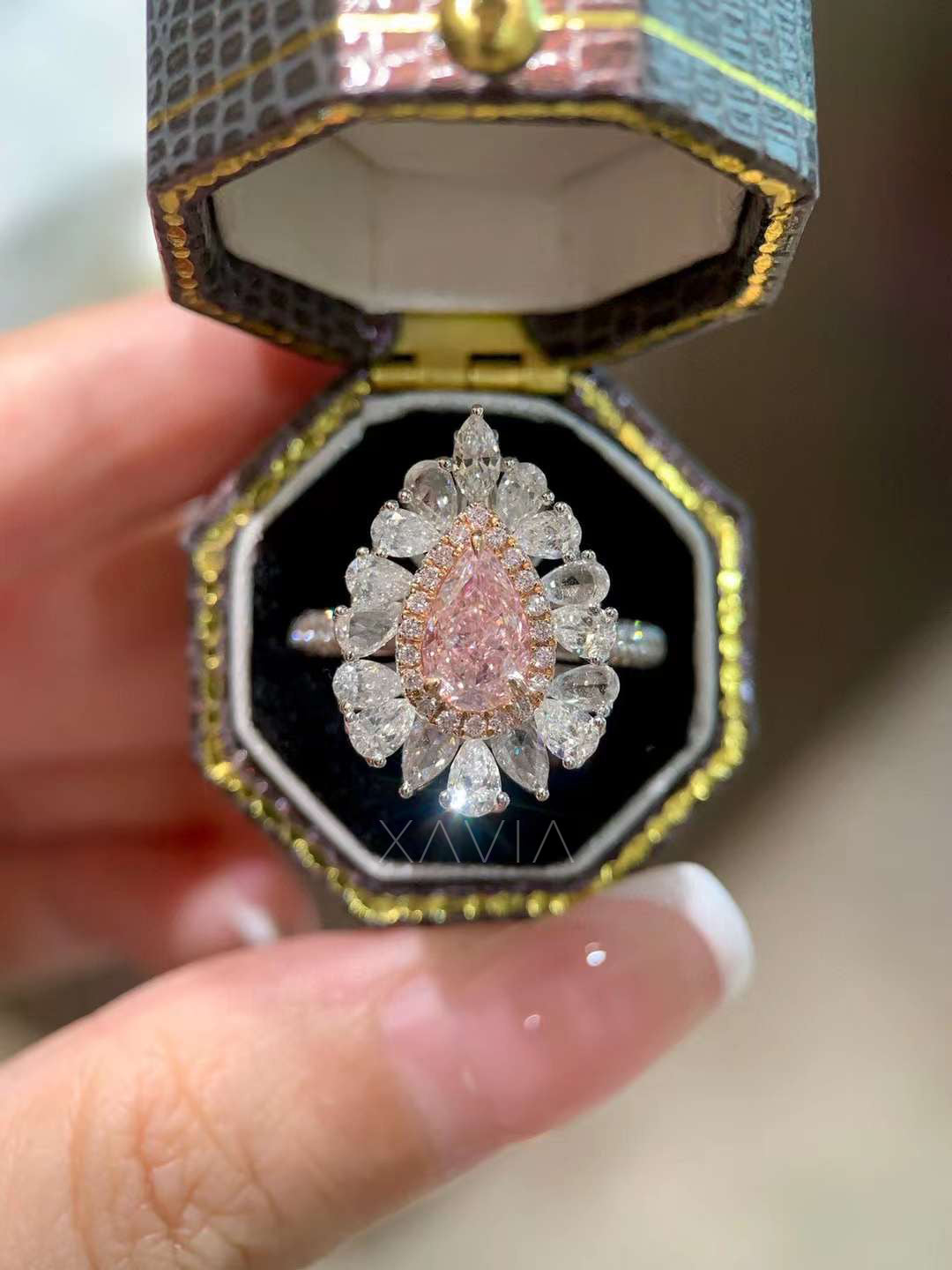 pink pear cut diamond engagement ring with floral marquise halo cluster displayed on model’s hand