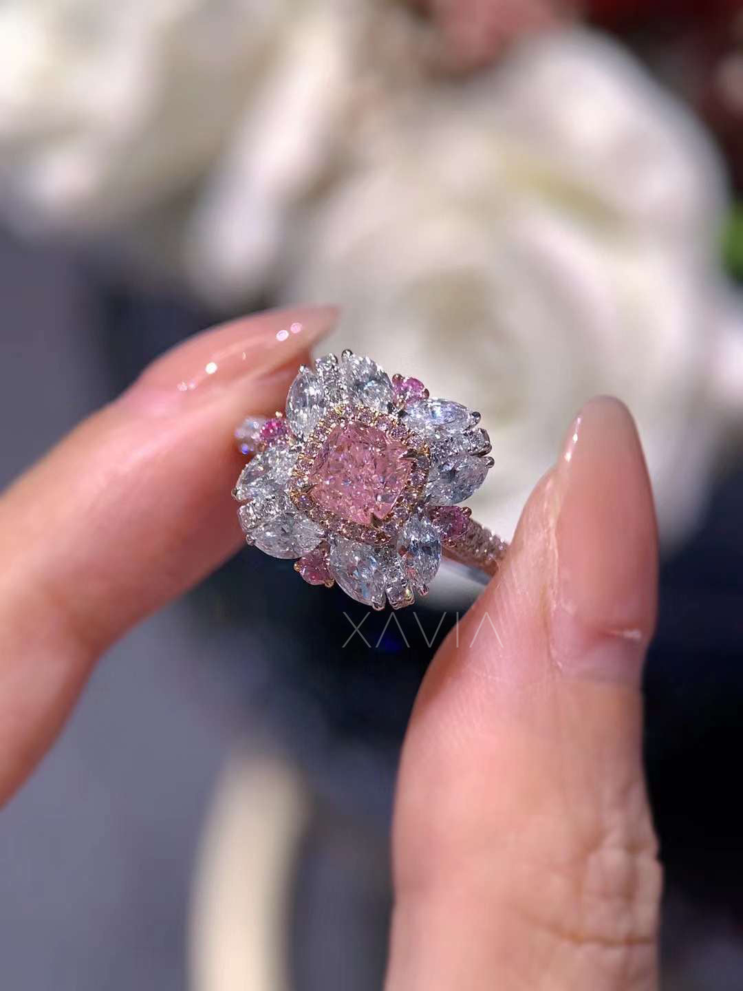 cushion cut pink diamond ring with floral halo held in hand