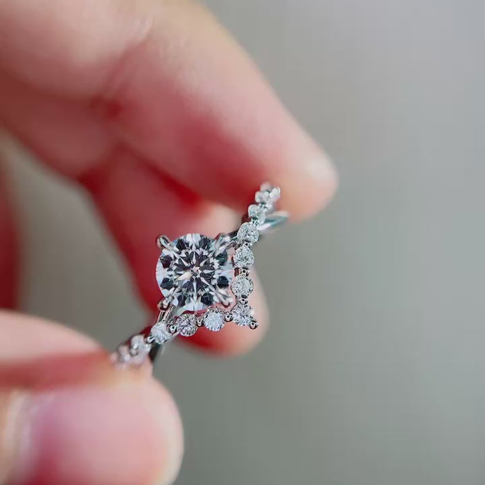 Angled front view of round cut lab grown diamond engagement ring emphasizing floral pavé detailing, sculpted vine band and elegant high polish white metal finish