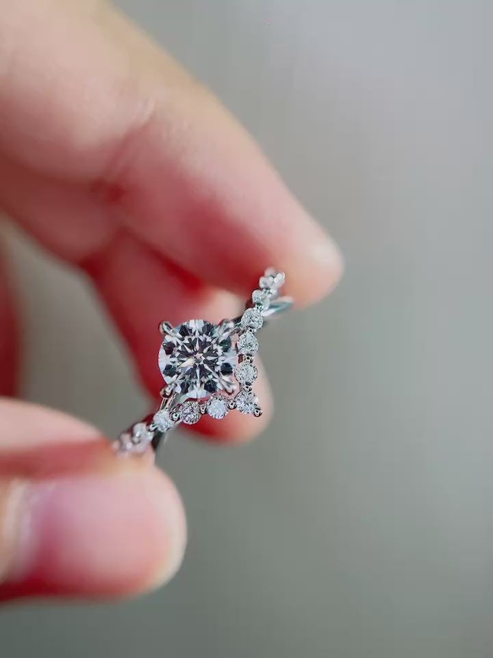 Angled front view of round cut lab grown diamond engagement ring emphasizing floral pavé detailing, sculpted vine band and elegant high polish white metal finish