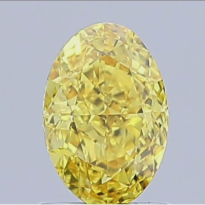 loose fancy vivid yellow oval diamond gemstone with brilliant cut facets against white background