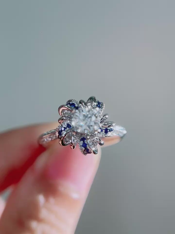 Round brilliant lab-grown diamond center framed by sculptural sapphire petal halo, pavé diamond shank and DEF VVS–VS clarity diamonds in solid gold.