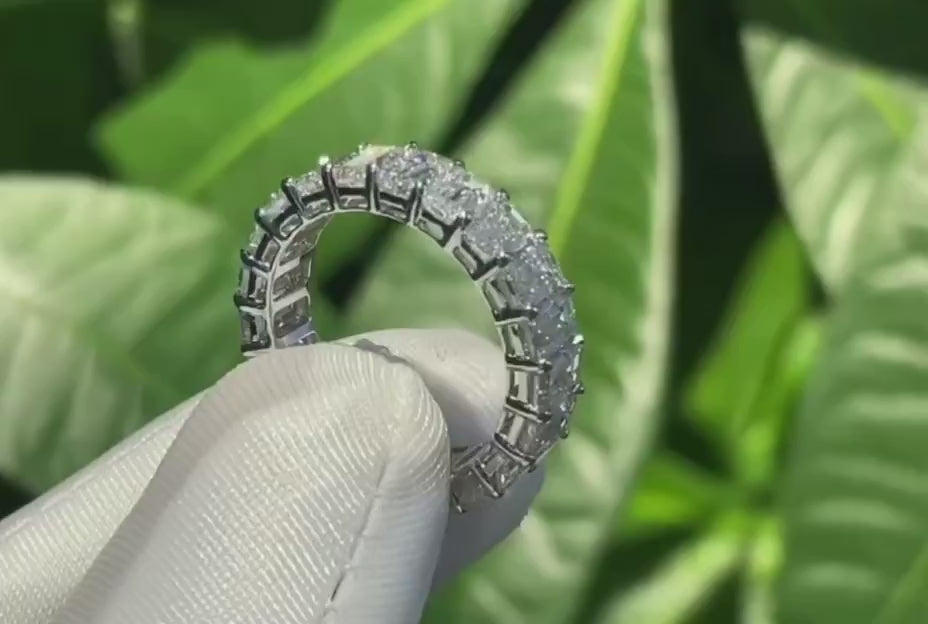 Emerald cut diamond eternity band in white gold, shown rotating under soft daylight to highlight shared prong setting, step-cut brilliance, and comfort fit design.