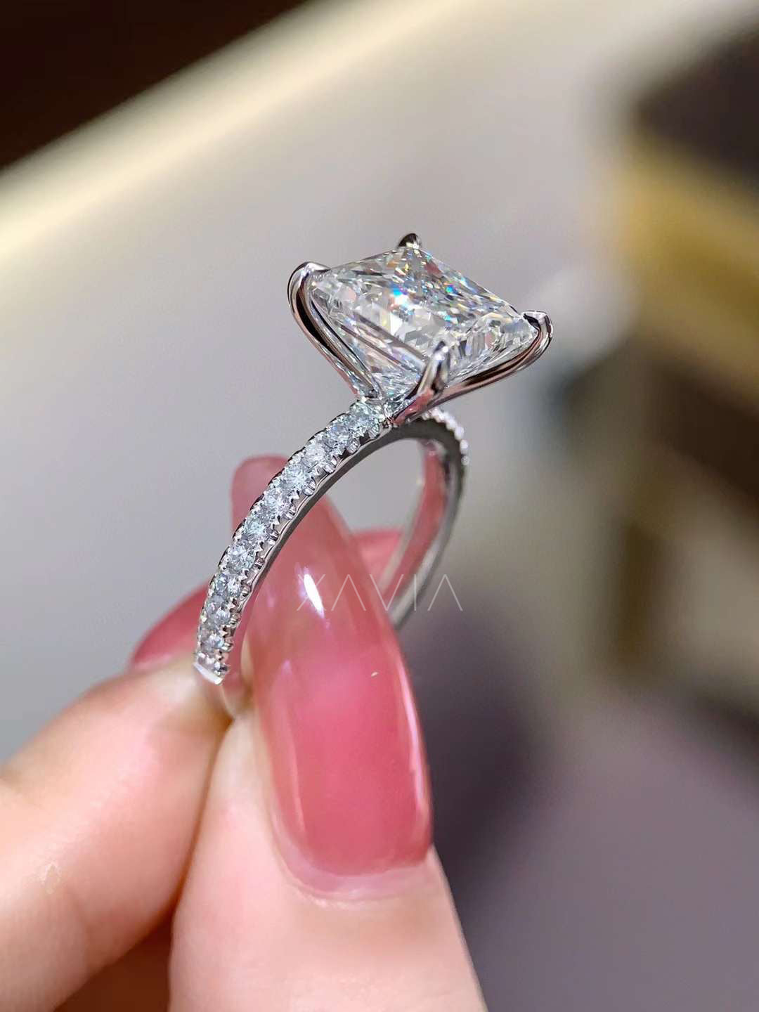 angled close up of princess cut lab grown diamond solitaire engagement ring with four prong setting and pavé diamond shoulders
