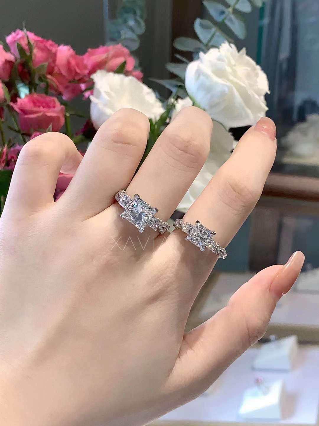 close-up of a platinum princess cut three-stone lab diamond engagement ring with pavé side stones worn on hand