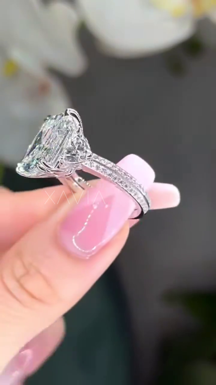 detailed profile view of platinum three stone cushion cut diamond ring with pavé band and trapezoid side stones