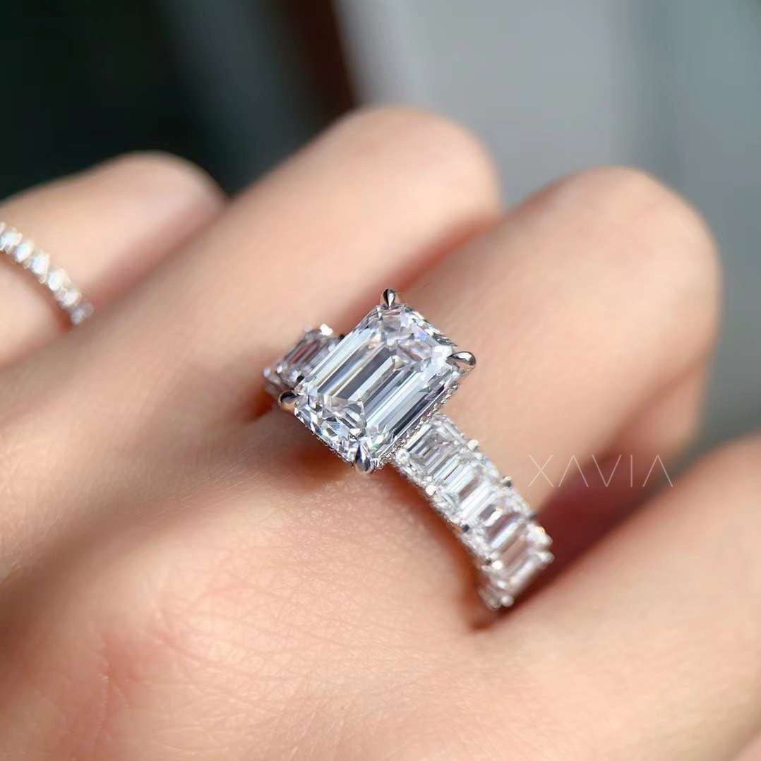 prong-set emerald diamond ring worn on hand with baguette band