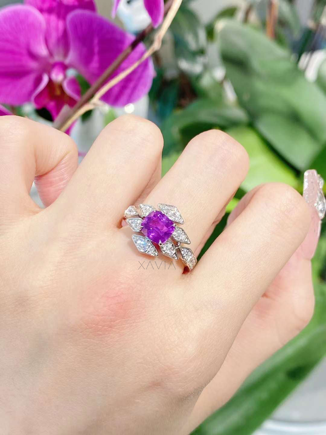 Cushion-cut purple center stone ring worn on hand, highlighting floral marquise diamond halo and elegant statement proportions