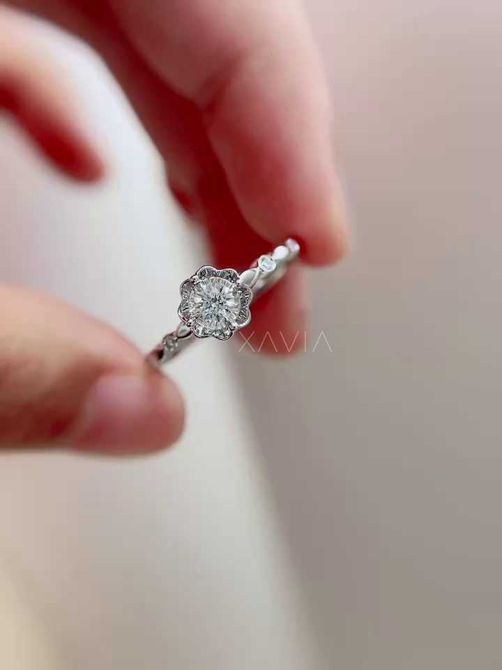 Roselith round lab-grown diamond floral halo ring held on fingers, showcasing petal-inspired halo design, sculpted band, and refined white metal finish.