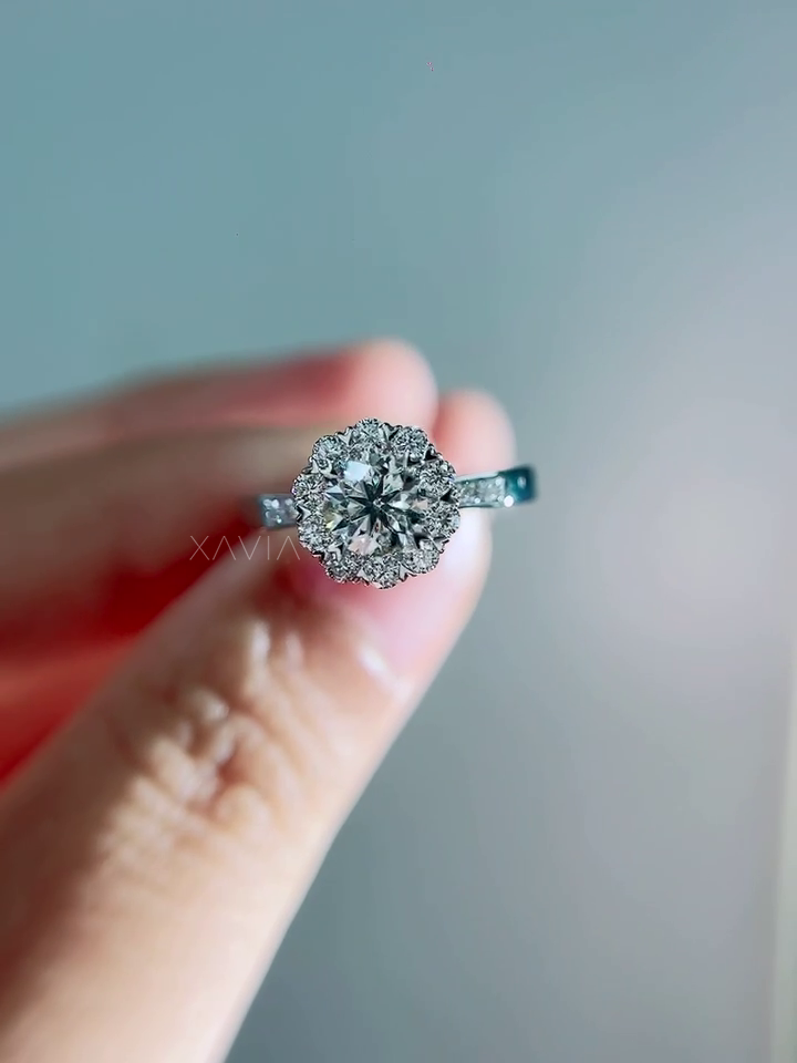 Soft lighting close-up of round brilliant diamond halo engagement ring featuring floral cluster halo and refined pavé band