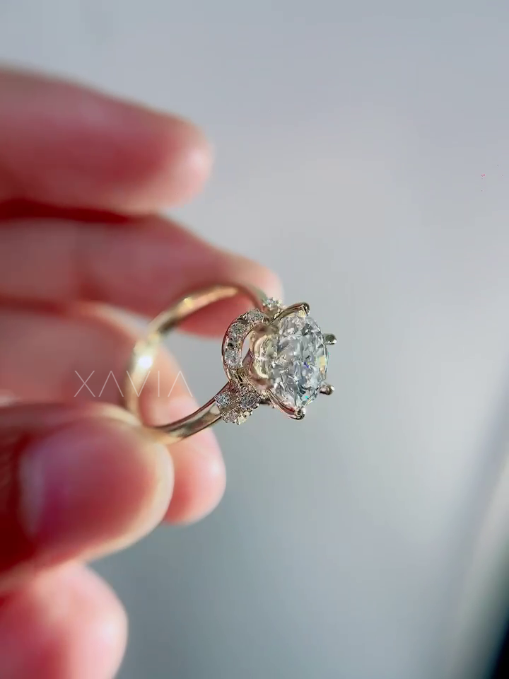 Top angle view of round lab grown diamond engagement ring with sculpted crescent hidden halo and delicate floral shoulder diamonds set in yellow gold cathedral setting