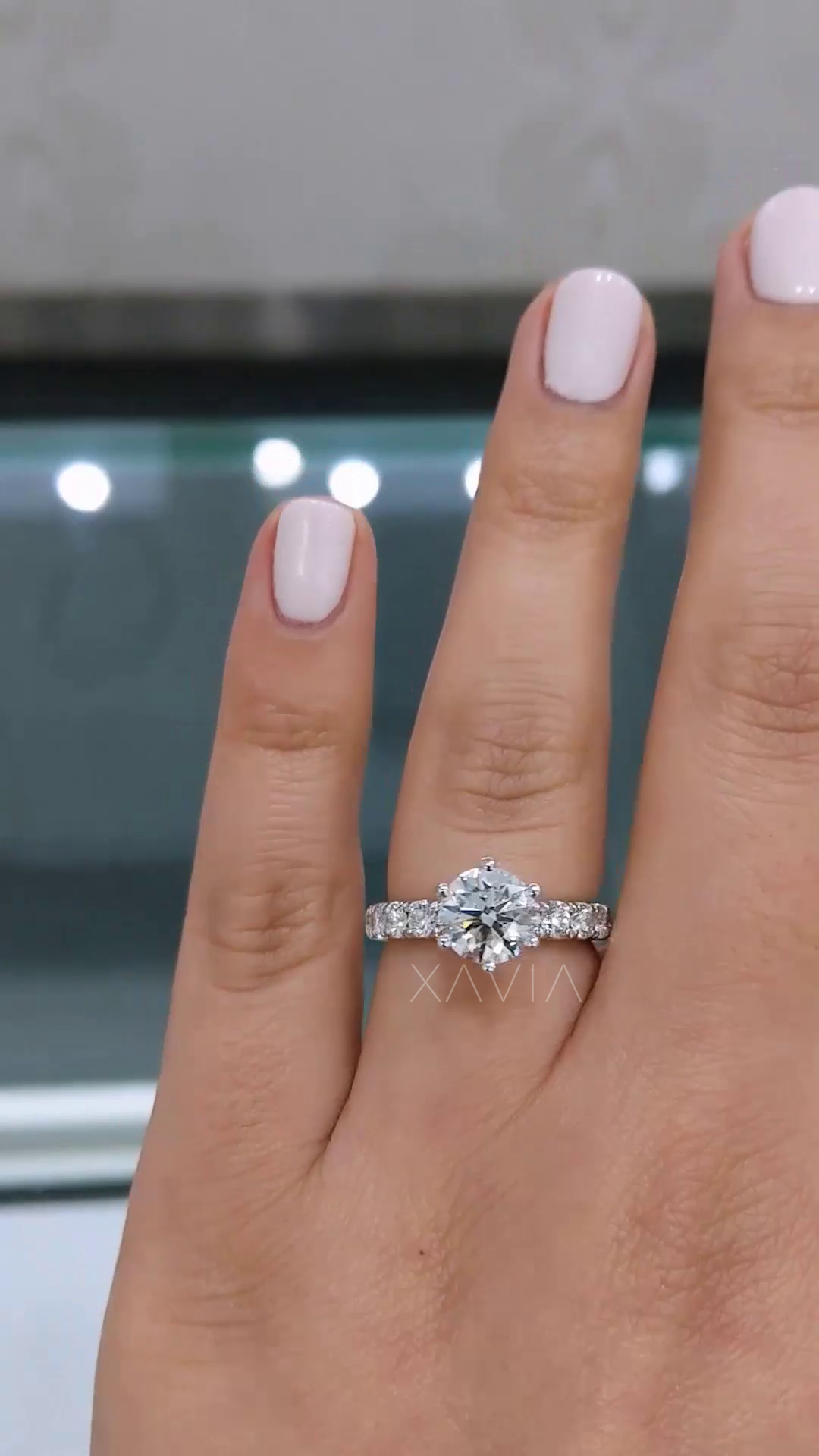 round brilliant lab grown diamond engagement ring with micro pave band worn on hand, featuring elevated six prong crown setting and refined solitaire design