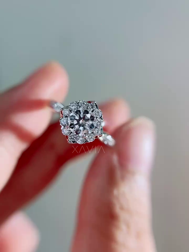 Close-up hand-held view of round brilliant lab-grown diamond engagement ring with round diamond halo and pavé cathedral band in polished white metal setting