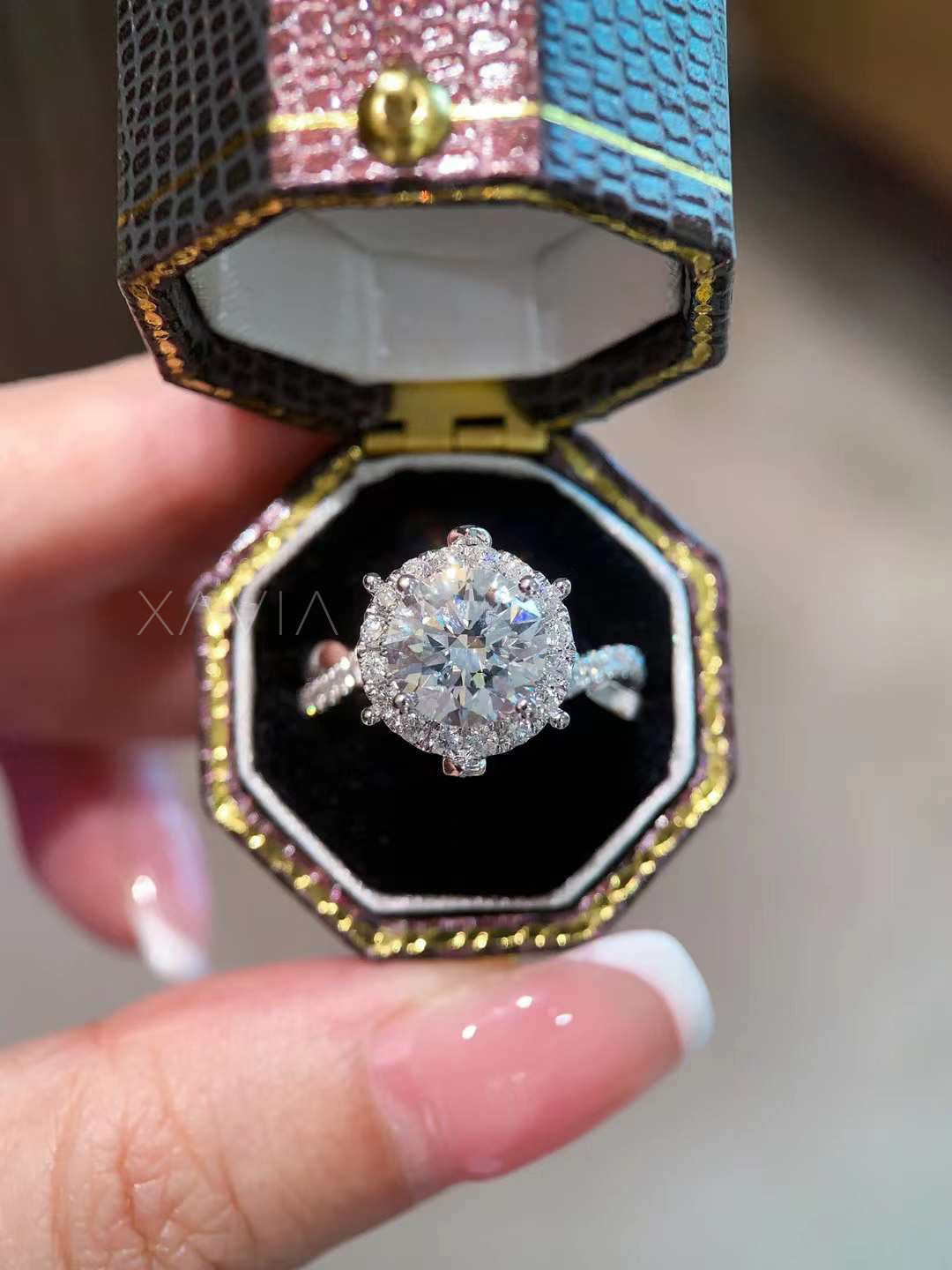 Round cut lab-grown diamond halo engagement ring in pavé setting, displayed inside an octagon luxury ring box with black velvet interior