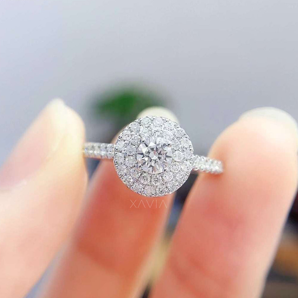 Round brilliant lab grown diamond halo engagement ring worn on hand, featuring double halo pavé setting and slim white gold band