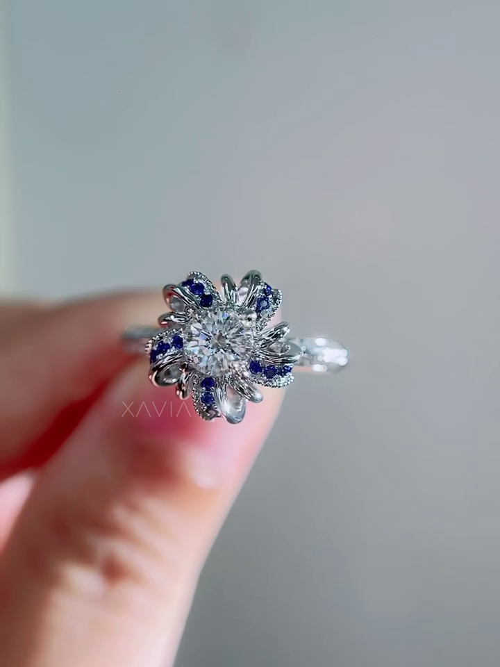 Front facing image of round lab grown diamond engagement ring featuring sculptural floral sapphire halo and pavé diamond band