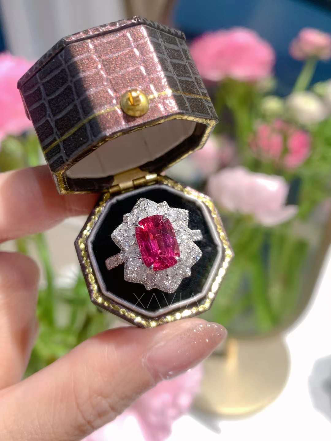 Cushion ruby and lab diamond halo ring displayed in cream velvet jewelry box with floral setting details