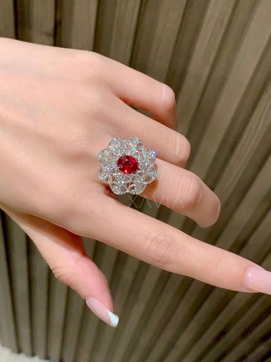 Oval ruby center floral cluster halo diamond ring worn on hand demonstrating bold cocktail ring scale with brilliant round diamond petals