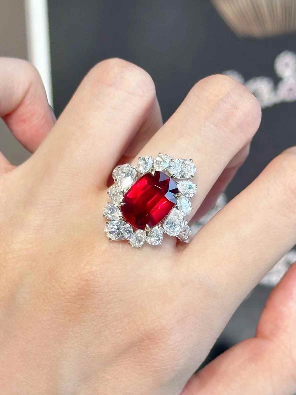 Cushion cut ruby red diamond halo ring worn on hand, showcasing pear shaped lab grown diamonds and bold statement cocktail design