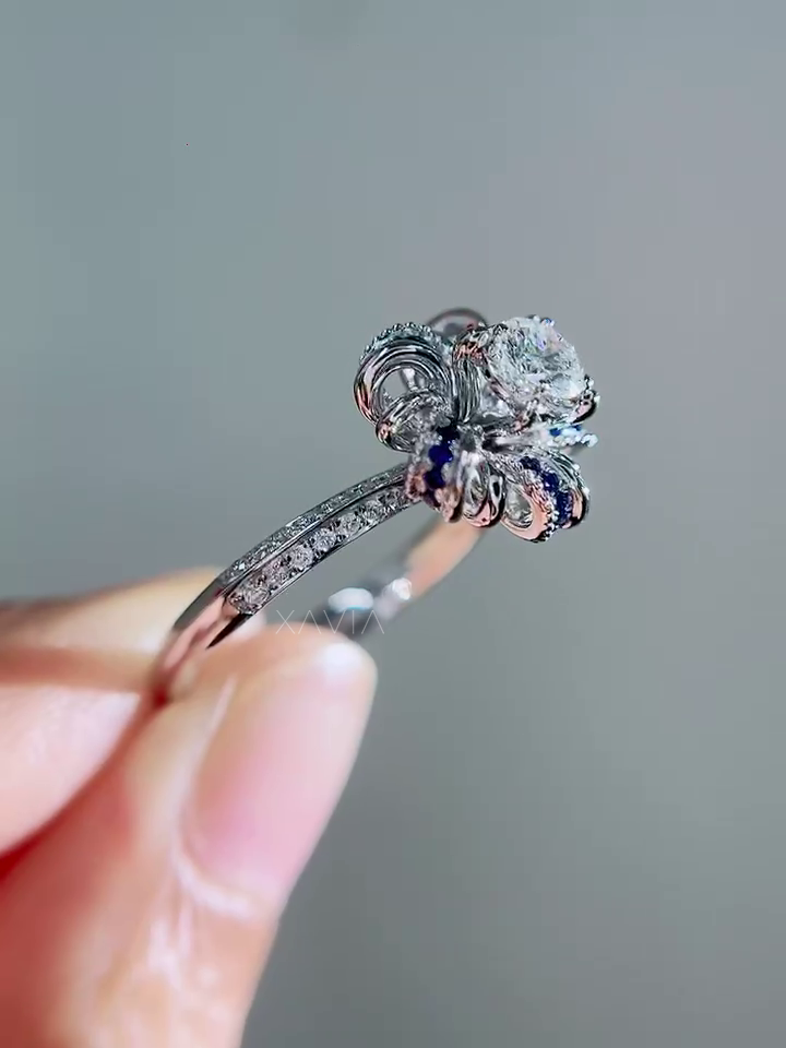 Close macro detail of sapphire accented petal halo surrounding round brilliant lab diamond center with pavé diamond detailing