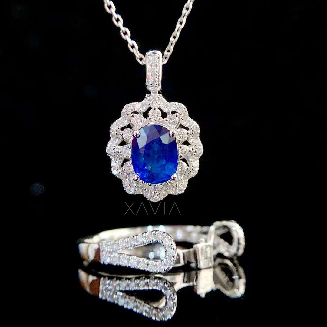 luxury oval blue sapphire halo pendant necklace displayed with matching diamond ring set showing floral cluster halo and pavé split shank jewelry design