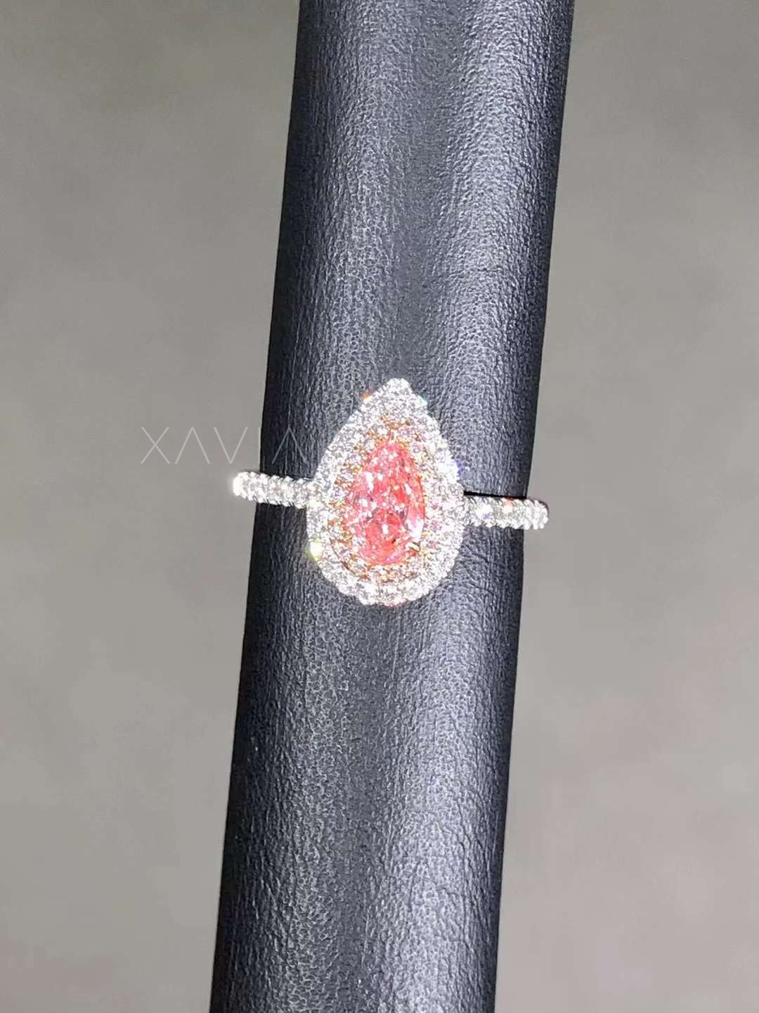 angled side view of pink pear lab diamond halo ring on display stand
