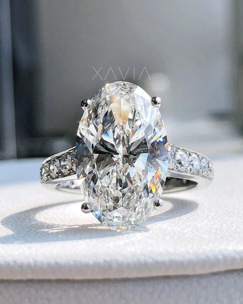 Side profile of platinum pavé band engagement ring featuring elongated oval cut lab diamond in four-prong setting