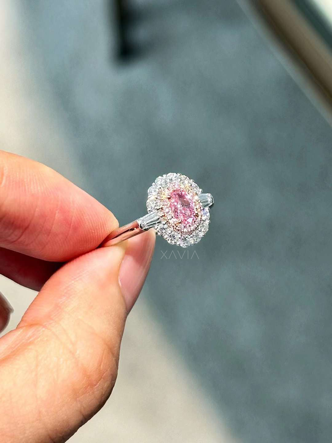 angled view of pink center diamond halo engagement ring with white baguette side stones