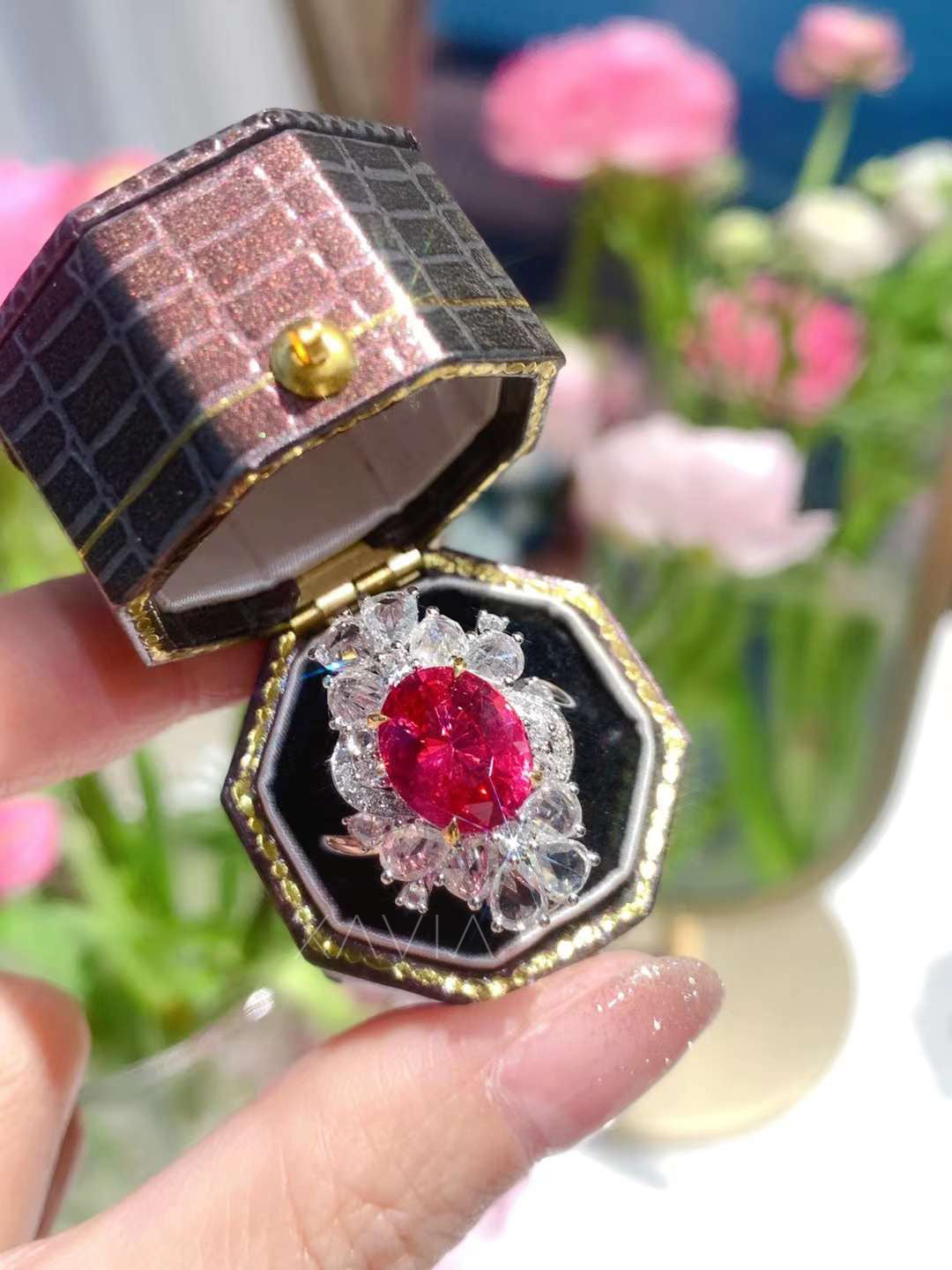 Side angled view of vivid oval ruby surrounded by marquise and pear diamond halo in platinum ring