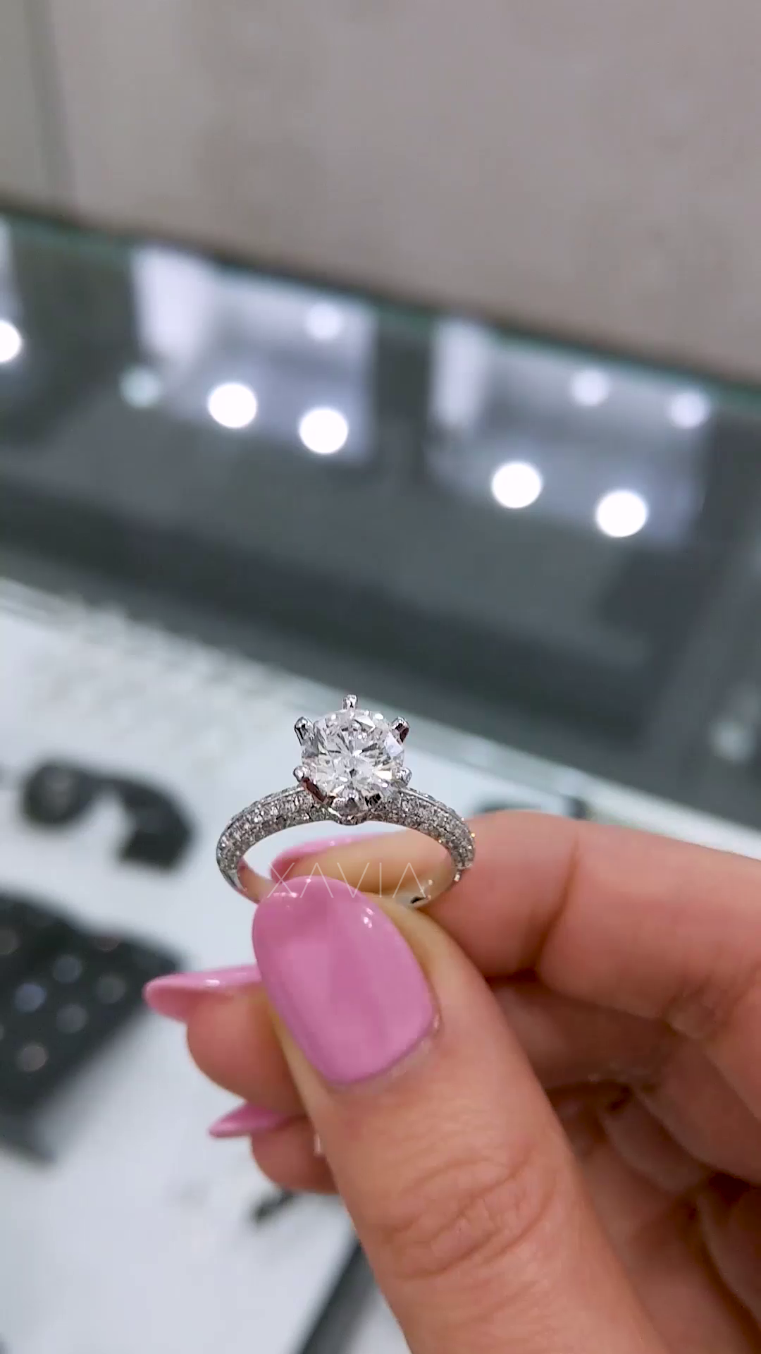 Front angle of round brilliant solitaire engagement ring with pavé diamonds along band and elegant six-prong head