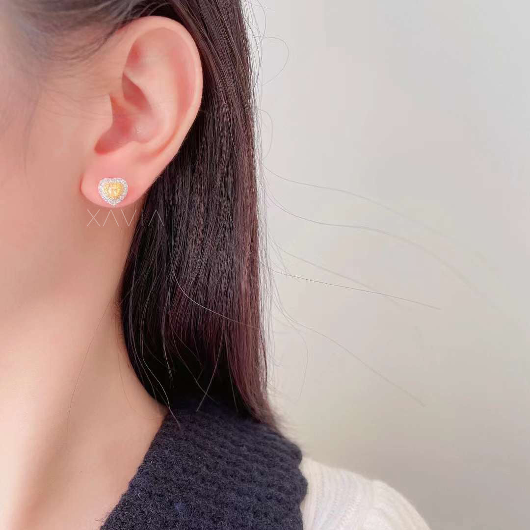 Yellow heart diamond earring with white halo worn on ear