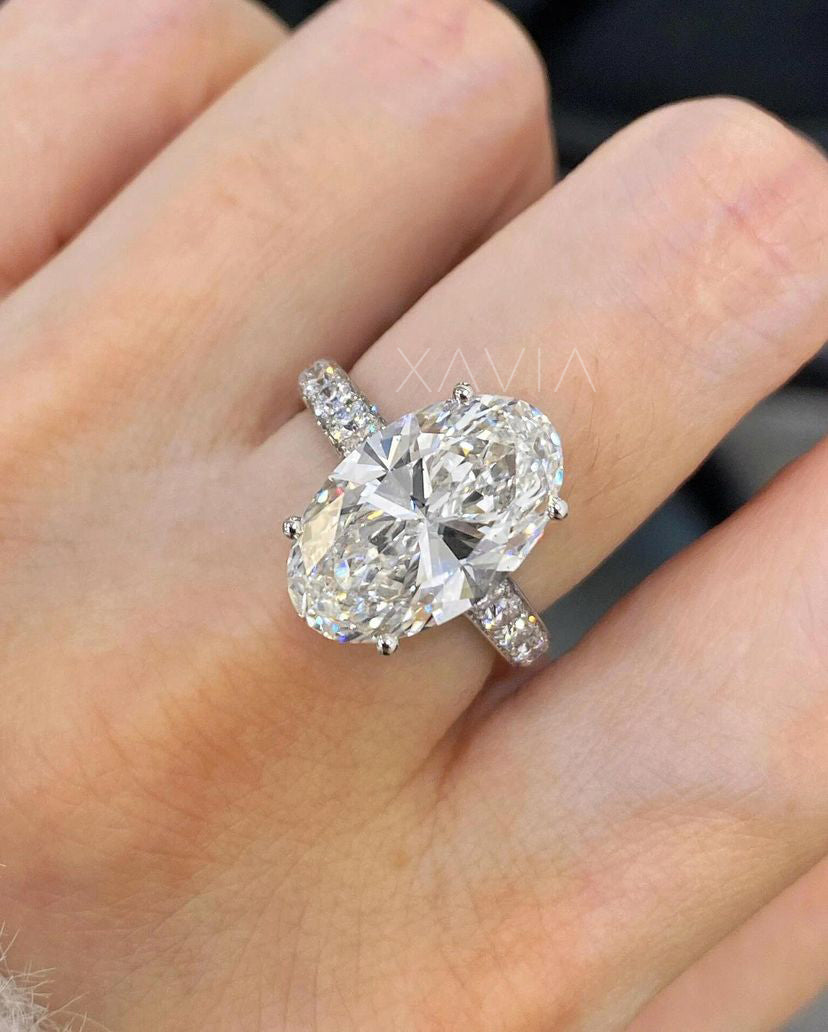 Top view of oval cut lab-grown diamond engagement ring with pavé round side stones in platinum look band