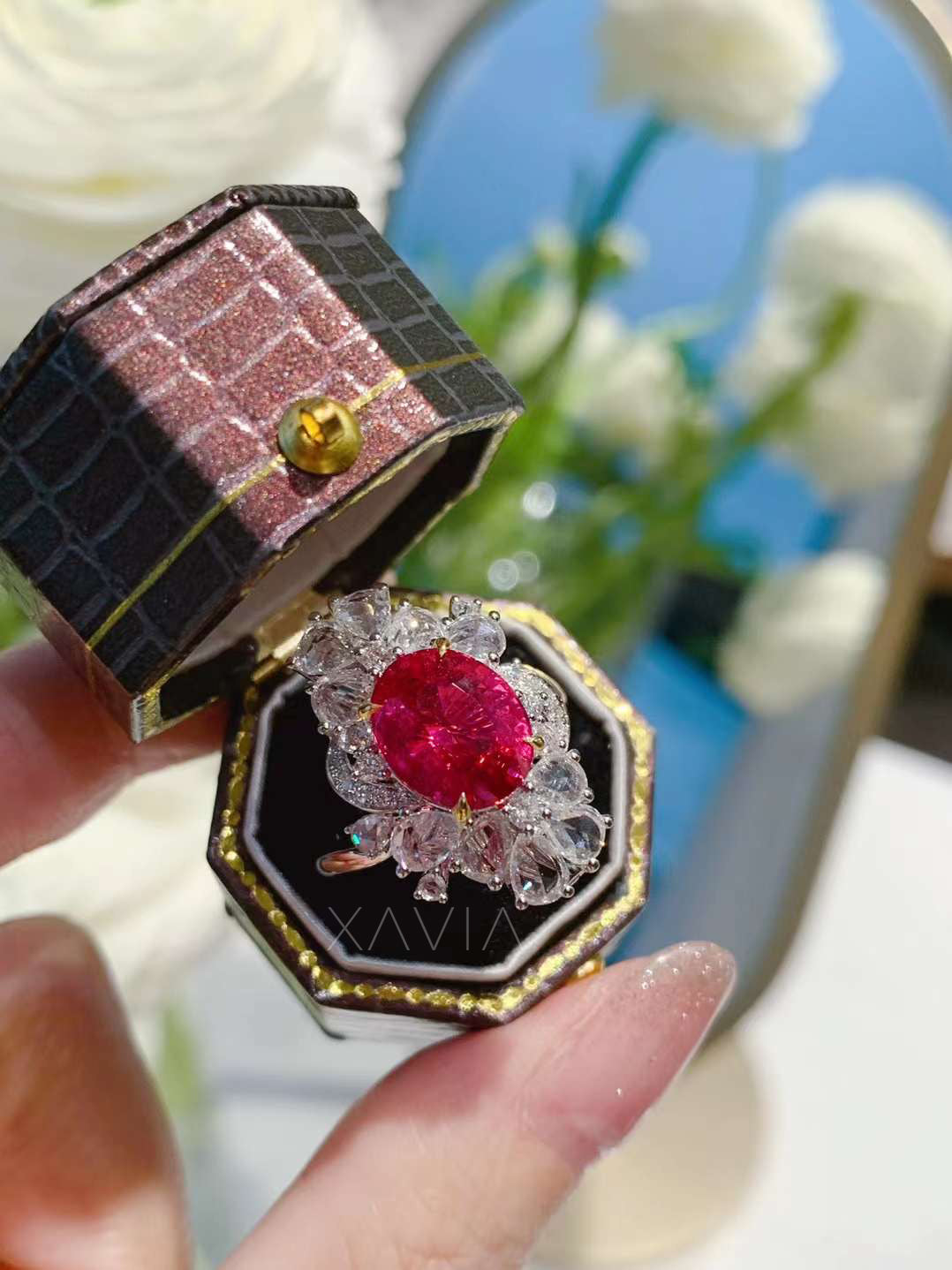 Top angle showcasing oval ruby center stone with surrounding floral halo of pear and marquise diamonds