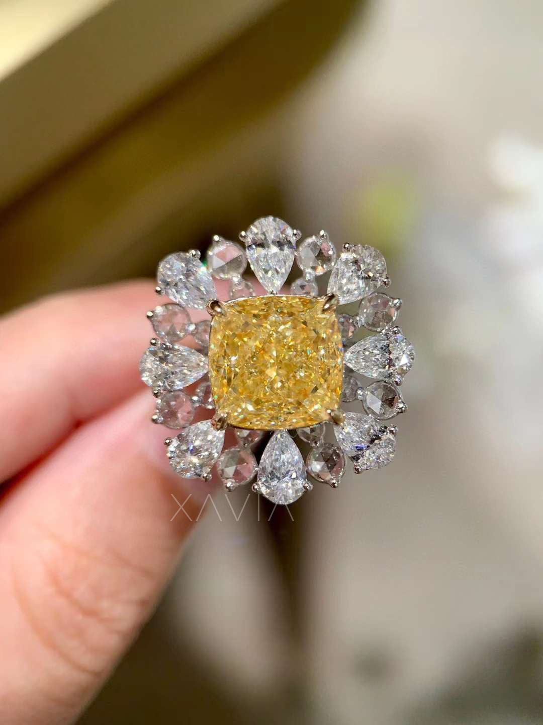 top-down angle of cushion fancy yellow diamond cocktail ring encircled by pear halo white diamonds, showing radiant floral-inspired arrangement