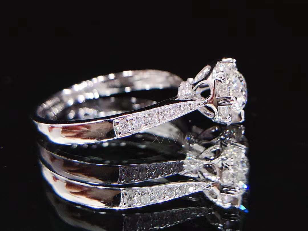 Top angle view of two round brilliant halo lab diamond engagement rings with pavé bands displayed on reflective black surface